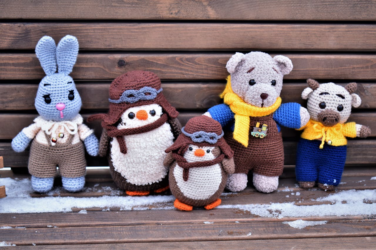 A charming collection of handmade crochet toys on a wooden bench in winter, showcasing unique designs.